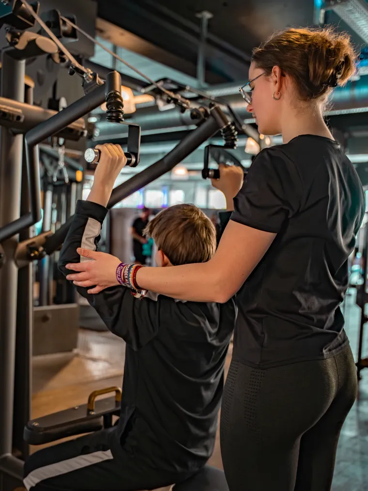 Trainer coacht ein Mitglied an der Trainingsstation